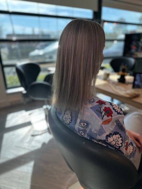 Vrouw met lang steil bruin haar in kantoorstoel met uitzicht op stad