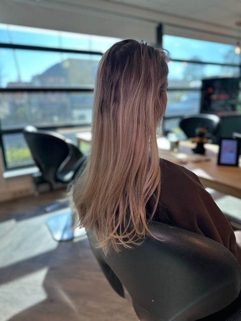 Vrouw met lang bruin haar aan bureau in kantoor met uitzicht op stad