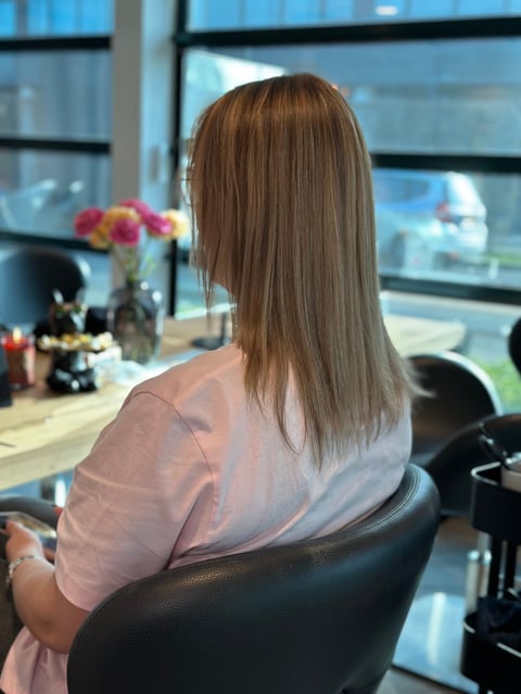 Vrouw met lang bruin haar aan bureau met uitzicht op stad