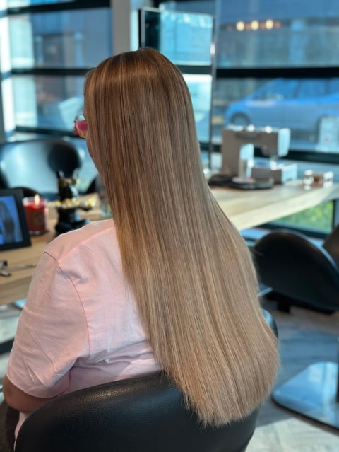 Vrouw met lang steil bruin haar in roze shirt aan bureau