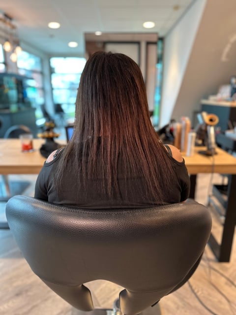 Vrouw met lang donker haar in kantoorstoel, zijaanzicht