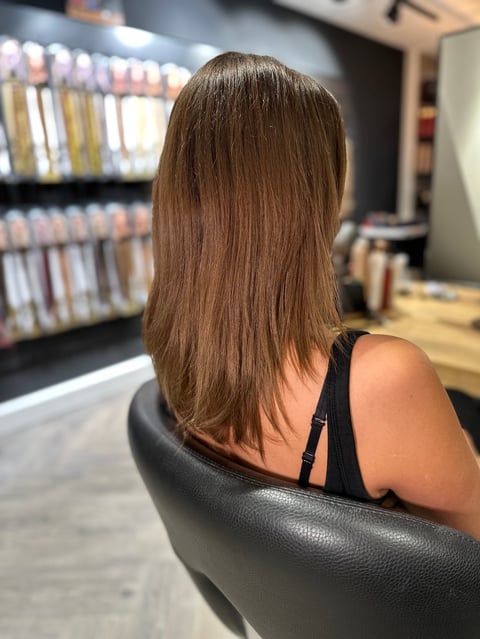 Vrouw met lang bruin haar in stoel voor boekenplanken