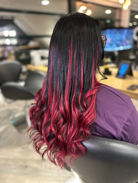 Vrouw met lang zwart haar met roze en rode ombre highlights