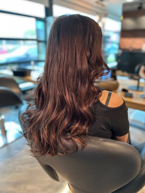 Vrouw met lang golvend bruin haar aan bureau