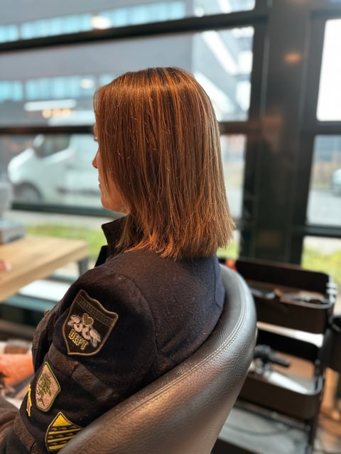 Vrouw met roodbruin haar in stoel bij raam